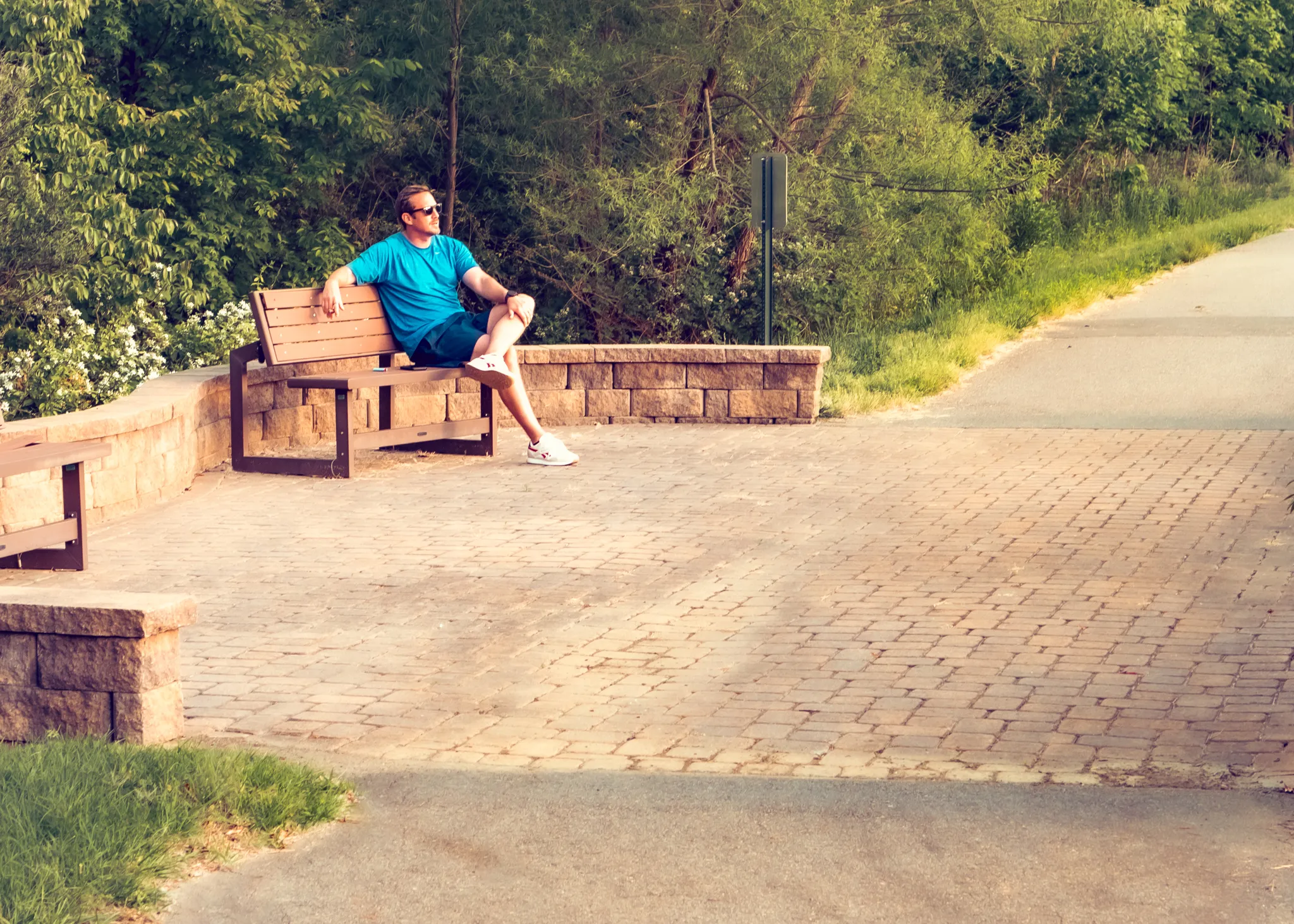 Man relaxing on bench next to the Fuda Creek Greenway